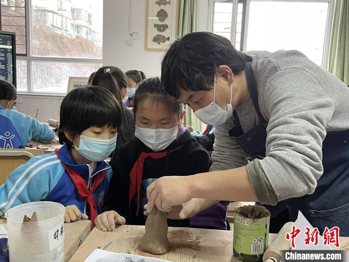 圖為西寧市勞動路小學(xué)教師賈煜與學(xué)生一起制作陶藝?！≈苋鸪阶?攝