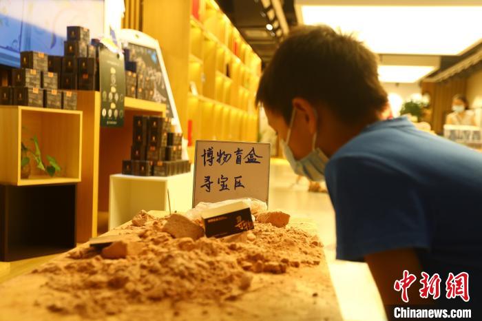 圖為在江西省博物館天工坊，一名小男孩端詳著已經(jīng)拆解完畢的“考古盲盒”現(xiàn)場(chǎng)。　劉占昆 攝