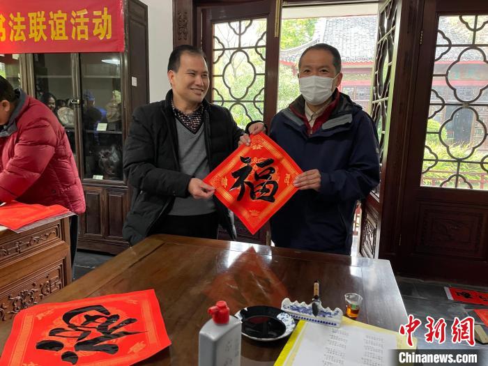 圖為一名日本人(右)展示其書寫的春聯(lián)。　林馨 攝