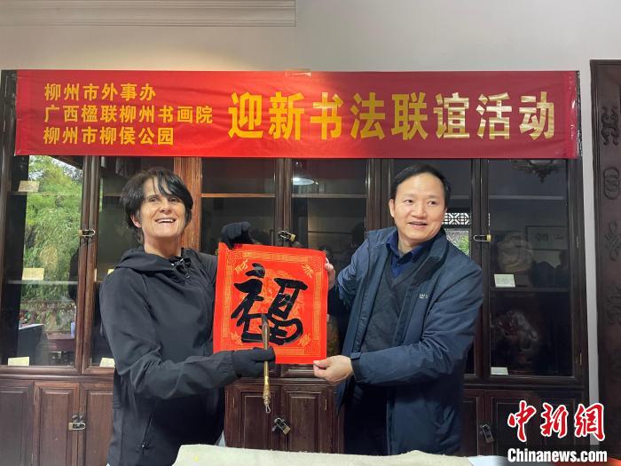 圖為一名英國人(左)展示其書寫的春聯(lián)?！×周?攝