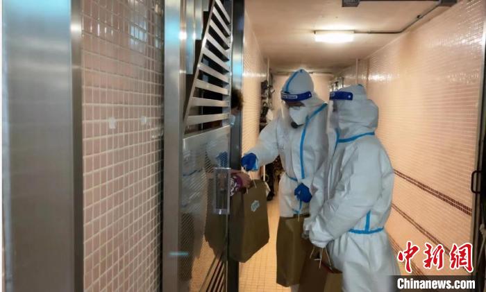 圖為吳學明和義工送抗疫物資到確診家庭手中?！∈茉L者供圖
