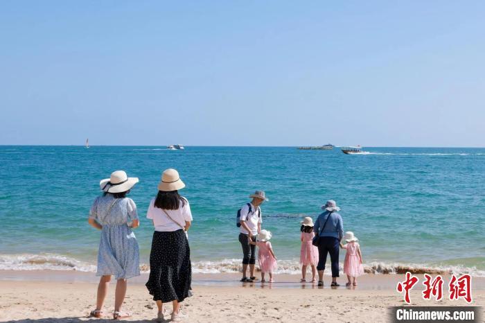 資料圖：家長帶著孩子在海邊嬉浪?！∮谓ㄐ?攝