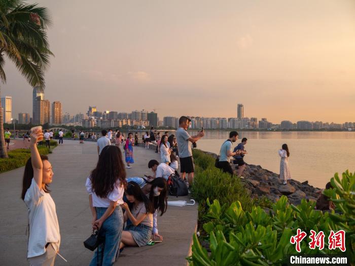 在海邊拍攝夕陽美景的游客?！×栝?攝