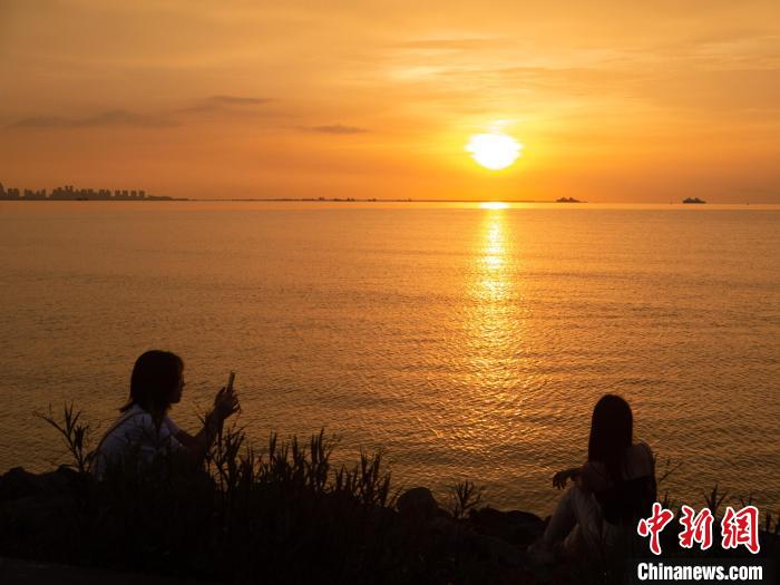 游客在海邊與夕陽美景合影?！×栝?攝