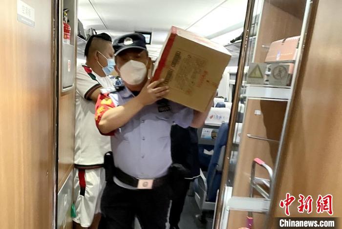 乘警扛著餅干等食物到車廂分發(fā)給旅客。　徐州鐵路公安處供圖
