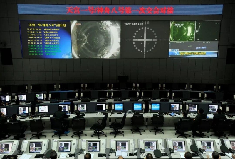 2011年11月3日凌晨，在酒泉衛(wèi)星發(fā)射中心指控大廳，技術(shù)人員通過大屏幕觀看天宮一號與神舟八號飛船對接全程。（圖源：央視新聞）