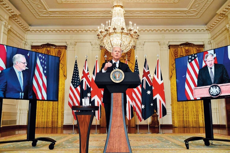 9月15日，美國總統(tǒng)拜登（中）在華盛頓白宮與英國首相約翰遜（右側(cè)屏幕中）和澳大利亞總理莫里森（左側(cè)屏幕中）舉行視頻會議