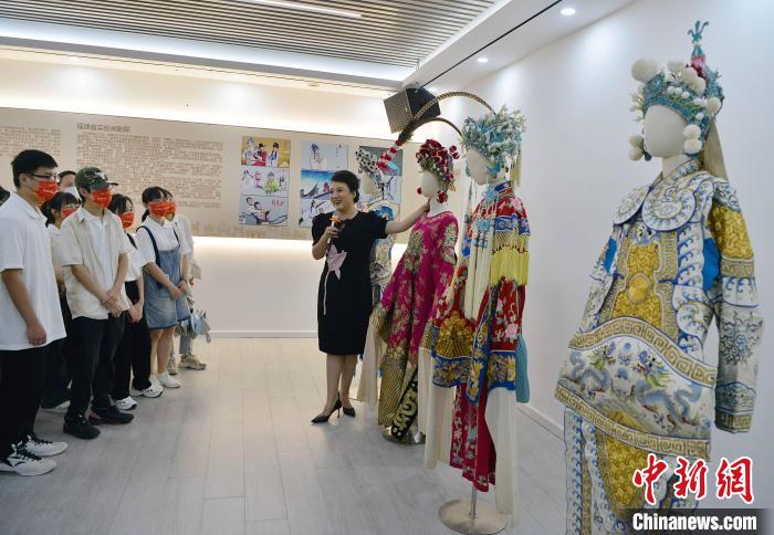 圖為福建省實(shí)驗(yàn)閩劇院工作人員為研學(xué)體驗(yàn)營學(xué)生介紹閩劇戲服?！埍?攝