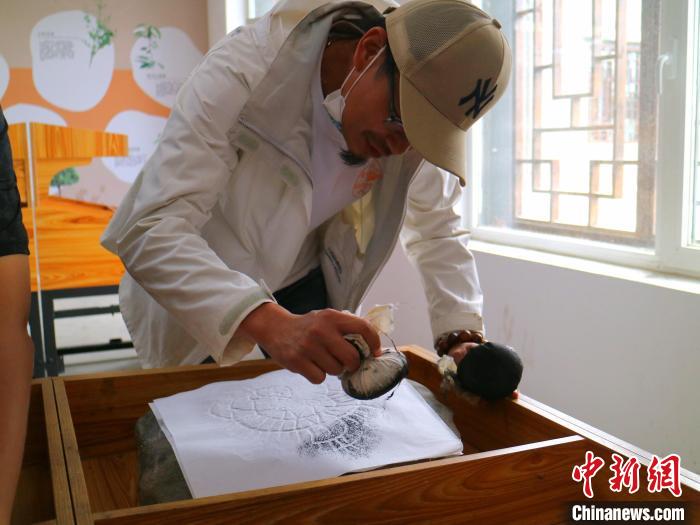 臺青用墨包為巖畫印記上色?！±钤?攝