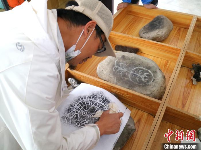 臺青用墨包為巖畫印記上色?！±钤?攝