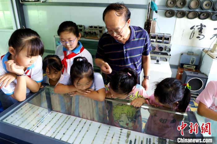 圖為肖光合正在給孩子們介紹收音機(jī)上的零件和電路原理?！∩筹w 攝