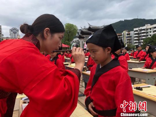 資料圖：在“點朱啟智”環(huán)節(jié)，先生在學(xué)童的額心點上朱砂，寓意孩子從此開啟智慧，目明心亮。曉東 攝