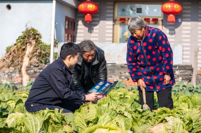 　江蘇省泰州市海陵區(qū)蘇陳派出所民警在蘇陳社區(qū)田間地頭向農(nóng)戶進行普法宣傳(2021年12月4日攝)。新華社發(fā)(湯德宏 攝)