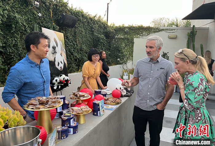 圖為中國駐洛杉磯旅游辦事處主任吳大偉（左一）向美國來賓介紹傳統(tǒng)的中秋佳節(jié)，邀請他們品嘗月餅。 <a target='_blank' href='/'>中新社</a>記者 張朔 攝