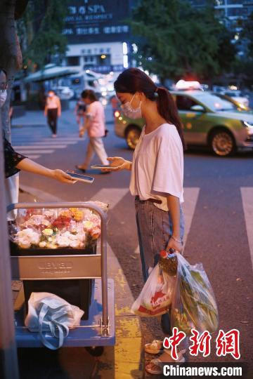 手提兩袋蔬菜的成都市民在選購鮮花?！∈茉L者供圖