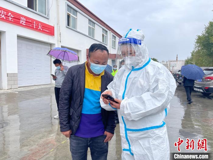 圖為王衛(wèi)玲(右)幫助做核酸的人員進行個人信息登記?！≈煊例?攝