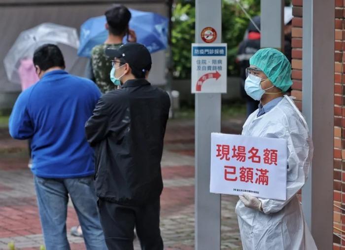 資料圖：臺灣快篩站現(xiàn)場名額額滿，醫(yī)護人員于排隊末端舉牌提醒。圖片來源：臺灣《聯(lián)合報》，記者 曾原信 攝
