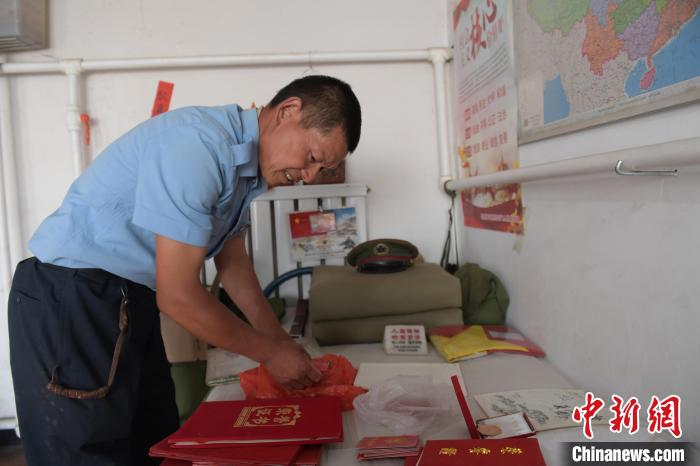 圖為謝建民整理當(dāng)兵時(shí)的榮譽(yù)證書(shū)?！『鷸|育 攝