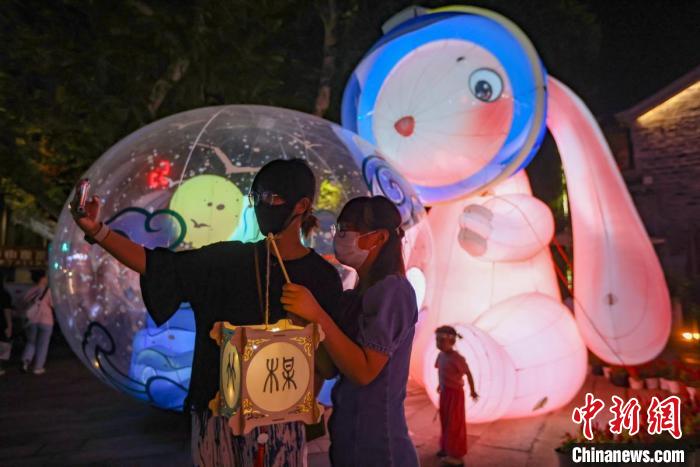 年輕人在燈市擺放著的“兔子燈”前留影?！°蟛?攝