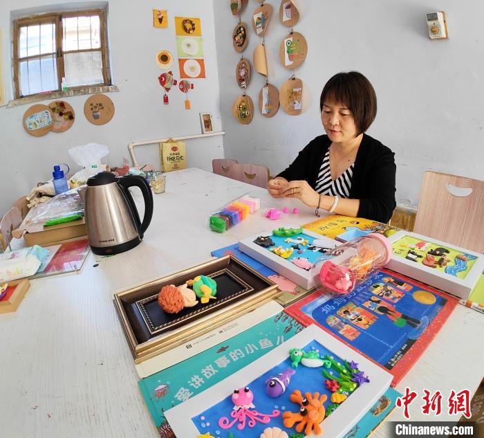 張美正在準備給孩子們講故事用的道具?！∠臅枣?攝