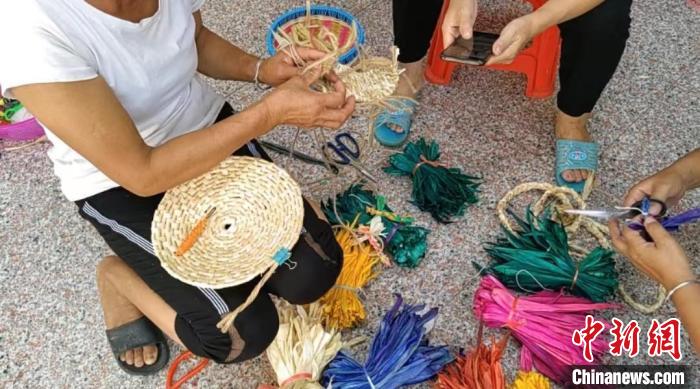 眾人正在用彩色玉米皮編織工藝品?！⒖÷?　攝