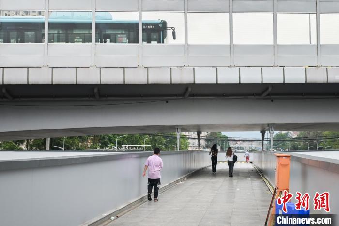 圖為市民走在天橋上，公交車從頭頂?shù)缆否傔^(guò)?！∨硇拟?攝
