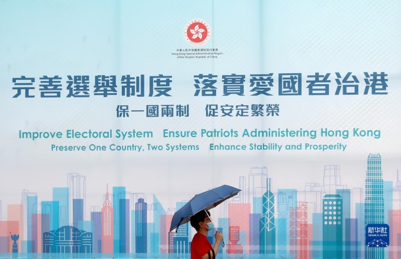 一名香港市民從“完善選舉制度 落實愛國者治港”巨幅海報前經(jīng)過(2021年3月31日攝)。新華社記者 吳曉初 攝