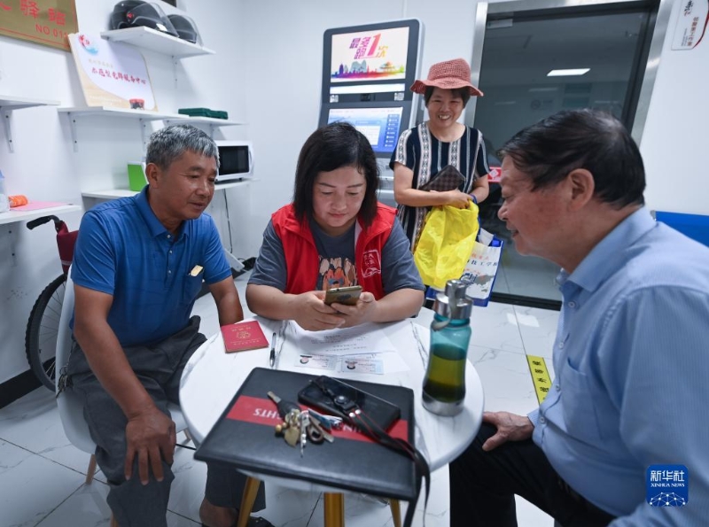 在浙江省杭州市臨安區(qū)玲瓏街道東山社區(qū)便民服務(wù)站，黨員志愿者幫助居民填寫公租房申請資料（2022年8月17日攝）。新華社記者 徐昱 攝