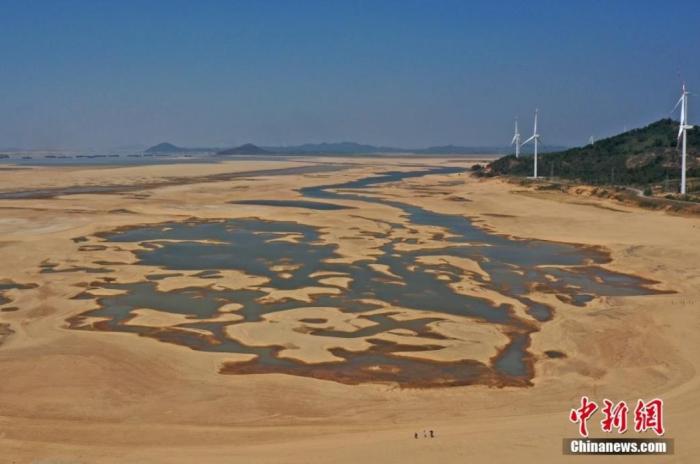 在江西省九江市都昌縣鄱陽(yáng)湖水域，干涸的湖床形成多個(gè)大小不同的水洼，幾名游客正在灘涂上行走。(資料圖) 劉占昆 　攝