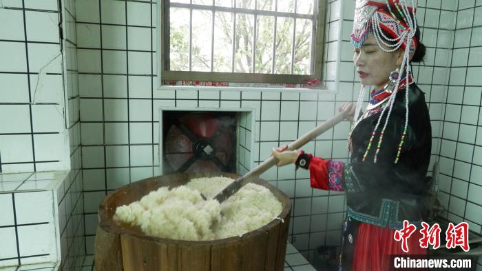 圖為藍春花鏟出煮熟的糯米進行釀酒?！∮浾呷A山 攝