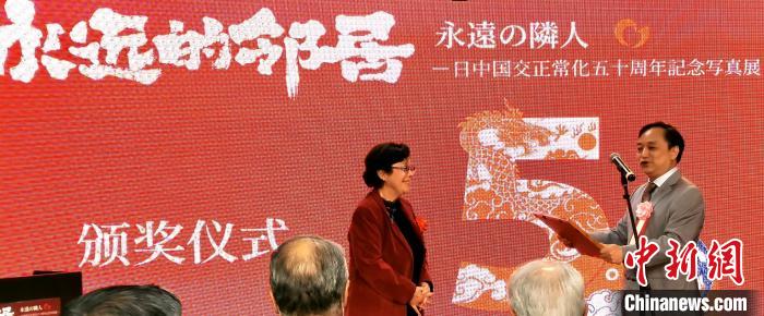 攝影展實(shí)行委員會中方代表劉莉生代表多元文化會館向日本前駐華大使阿南惟茂夫人阿南史代頒發(fā)獎狀?！≈鬓k方供圖