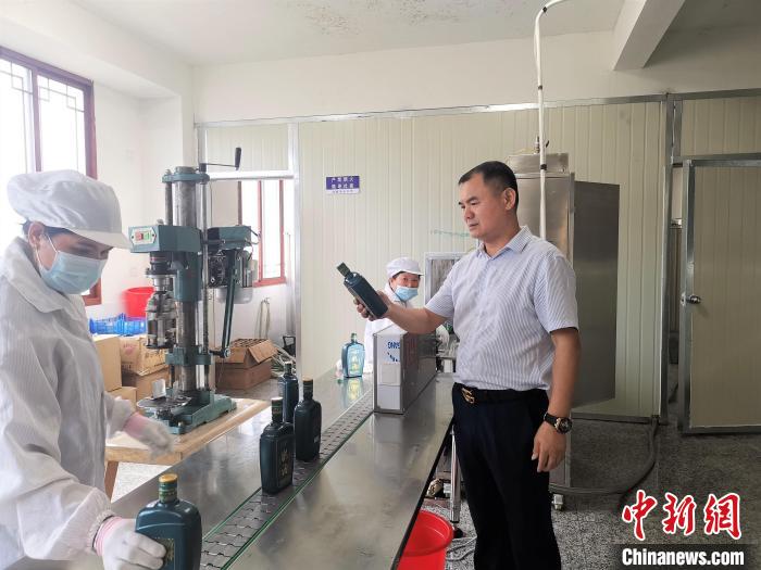 吳善遠(右一)檢查黃酒包裝是否達標?！∑聊峡h委組織部 供圖