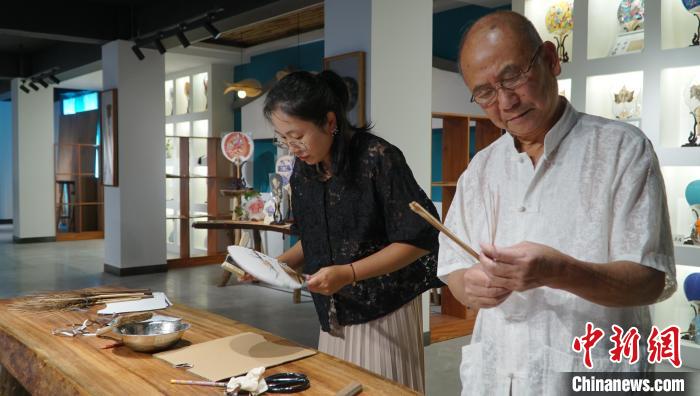 黃碩夫(右)和女兒黃可人(左)一起制作團扇?！±顙申?攝
