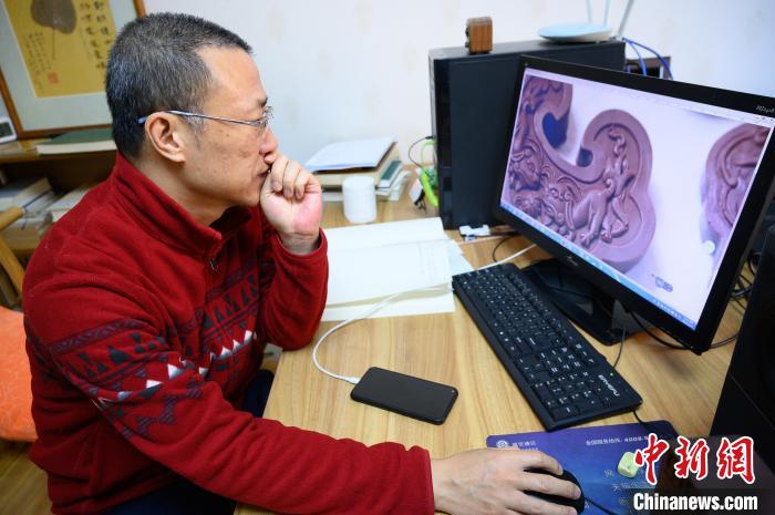 孫晟坐在電腦前，瀏覽設計成品圖片?！№f亮 攝