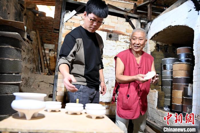 在窯口，林俊徒弟把已上釉的素坯傳給師傅。　張金川 攝