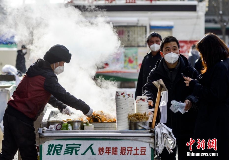 資料圖：外出購物的市民購買品嘗街頭小吃。 劉新 攝