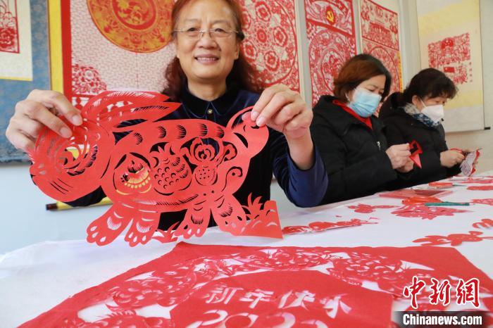 非遺傳承人董雙強(qiáng)在展示自己創(chuàng)作的剪紙作品?！±詈?攝