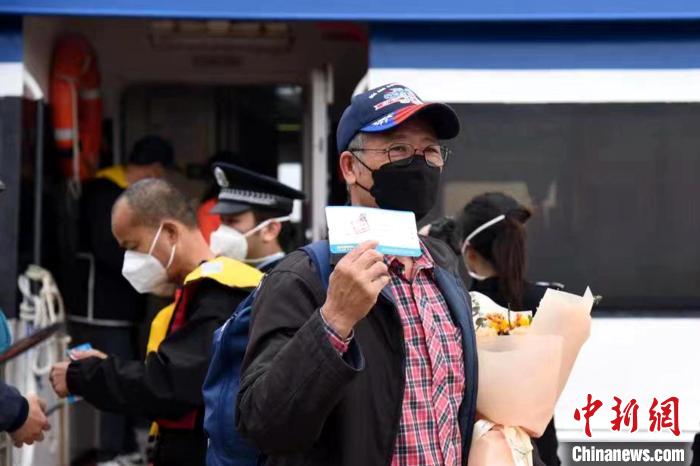搭乘泉金航線的乘客展示手中的船票?！∪?攝