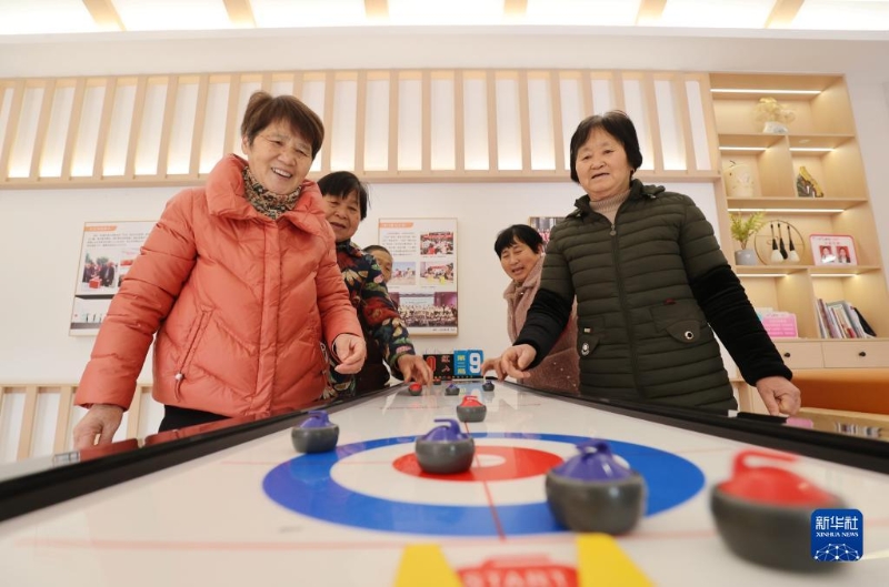 2月16日，在湖州市德清縣阜溪街道興山未來(lái)社區(qū)居家養(yǎng)老服務(wù)中心，社區(qū)老人在打“桌上冰壺球”。（圖源：新華社）