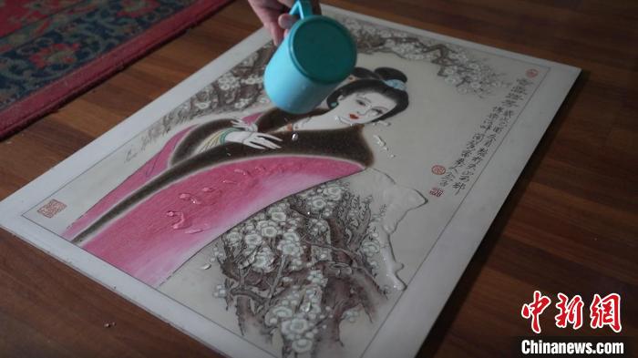 藺烈演示在板刻線畫作品上做防水試驗，展示作品不僅防水還不掉色，濕水后還可用布擦拭?！∪诸?攝