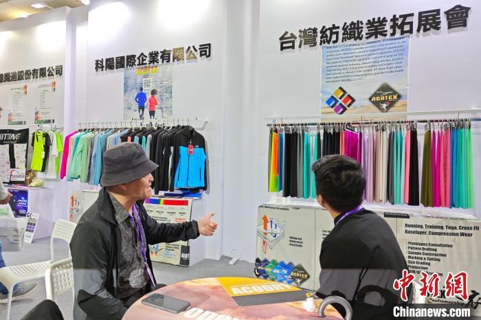 臺(tái)商邱鶴銘(左)在展位上介紹新研發(fā)的功能面料?！枪跇?biāo) 攝