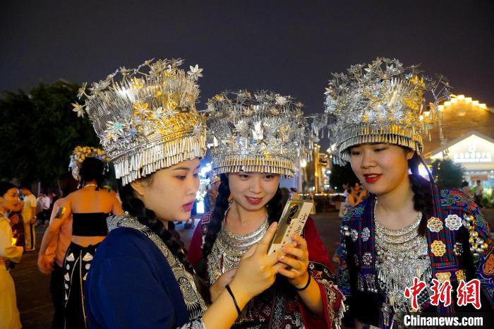 圖為身著苗族服飾的游客正在翻看照片?！№f國政 攝