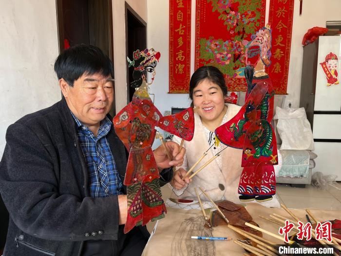 圖為馮克獻(xiàn)和女兒展示制作完成的皮影道具?！●R瑾 攝