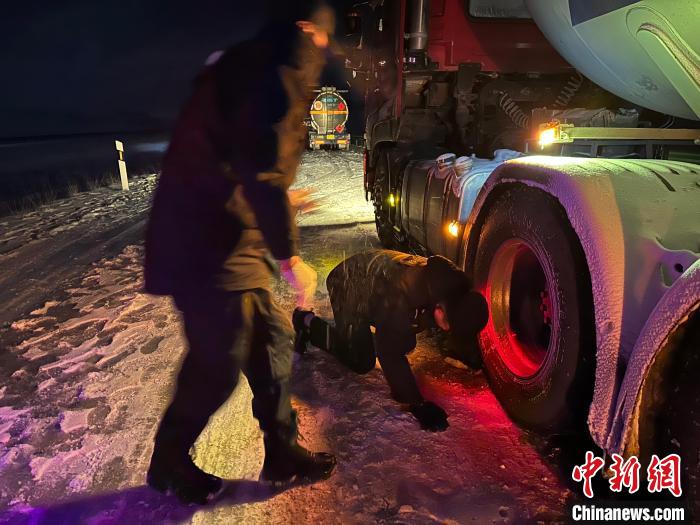 圖為民警幫助受困車輛安裝防滑鏈。　果洛州委宣傳部供圖