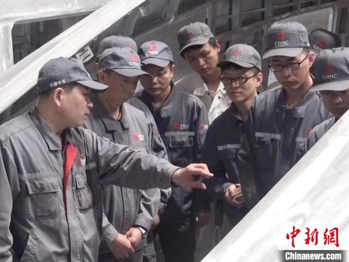 周晶輝正在為徒弟們講解司機(jī)室前窗框平度控制?！∈茉L者供圖