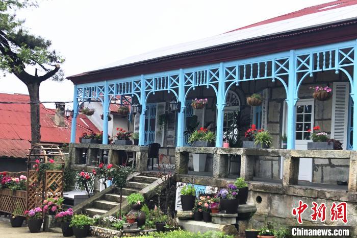 走進(jìn)喬尼·約翰遜在廬山上租住的別墅，藍(lán)色敞開(kāi)式外廊，一排石條凳上平均間隔的木頭柱支撐著拱券。　吳鵬泉 攝