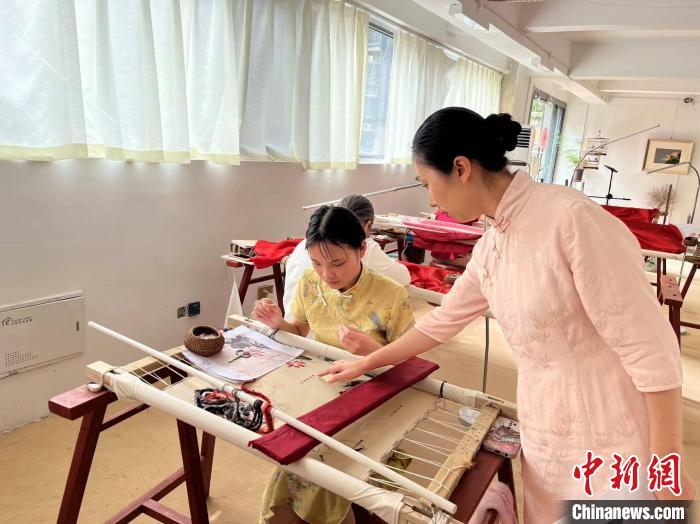 圖為陶衛(wèi)華正在指導(dǎo)繡坊的繡娘刺繡。　李韻涵 攝