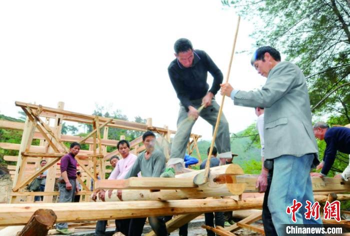 資料圖為木拱廊橋建造過(guò)程中，匠人們正在“搭屋架”?！↓徑?攝