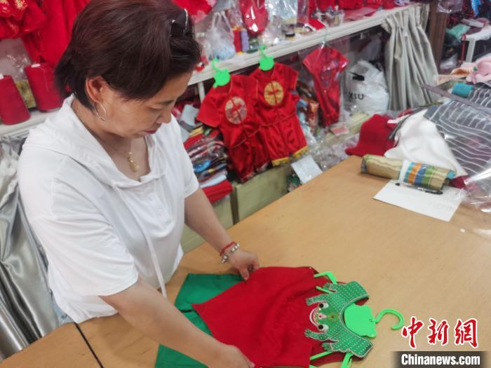 圖為勝芳古鎮(zhèn)一家兒童傳統(tǒng)服飾店，店員正在整理剛做好的青蛙衫?！⌒蟻喣?攝