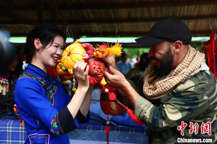 圖為一名來自德國的游客與身著民族服裝的壯族姑娘互動。　楊必盛 攝